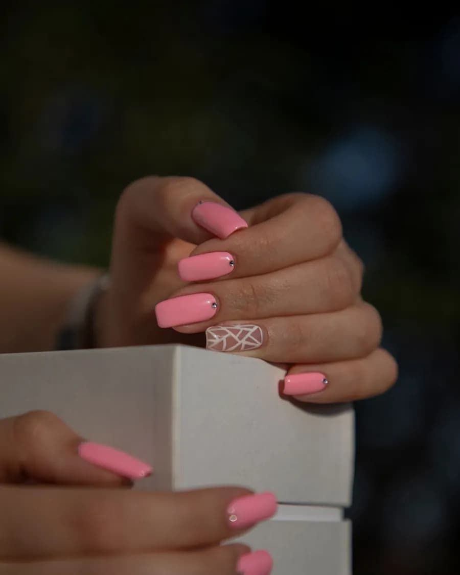Croix Rose — Un rose franc et un motif géométrique fin sur l'ongle d'accent.
